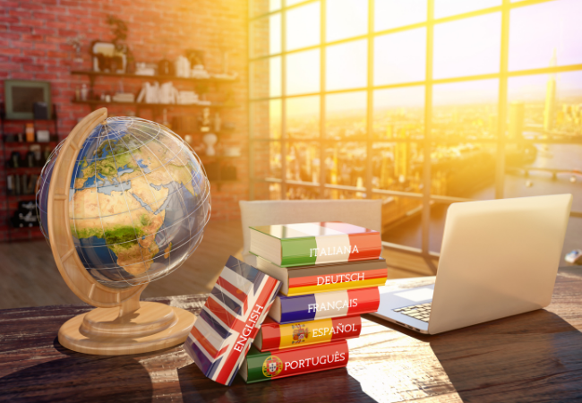 A table holds a globe, dictionaries in different languages, and a laptop; all essential tools of a professional translator.